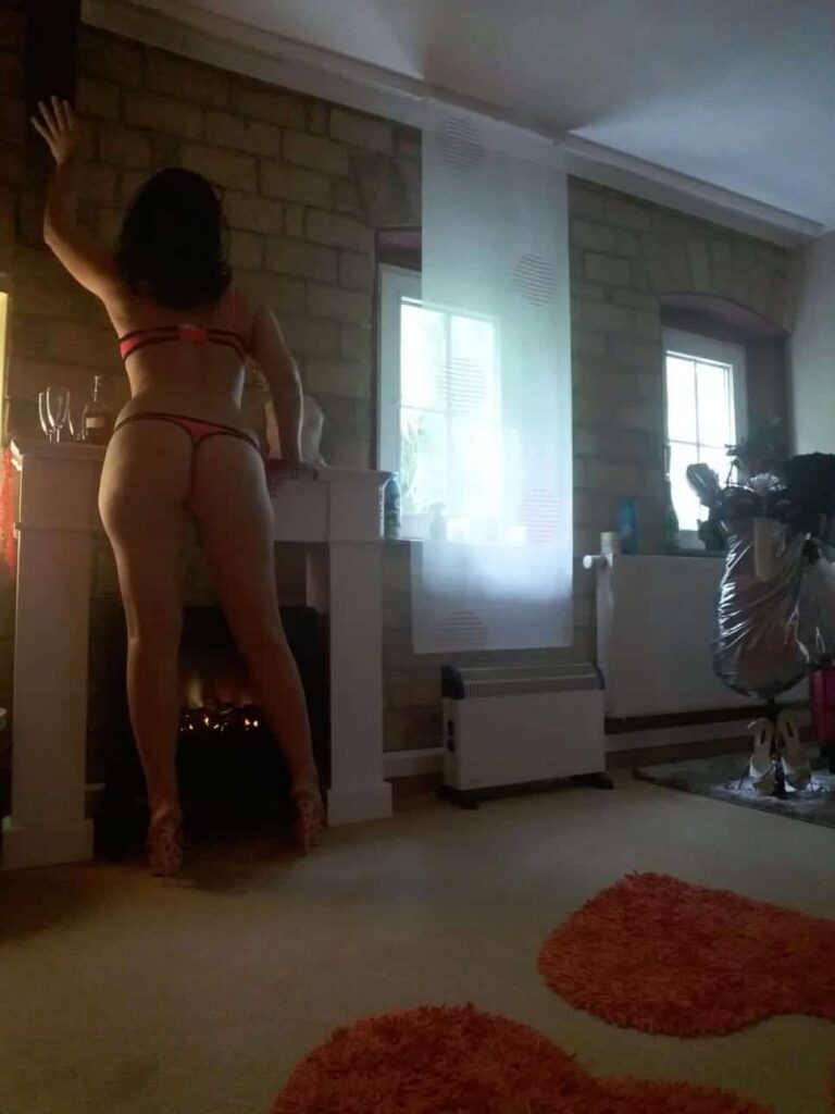 Katrin in roten Dessous von hinten am Fenster