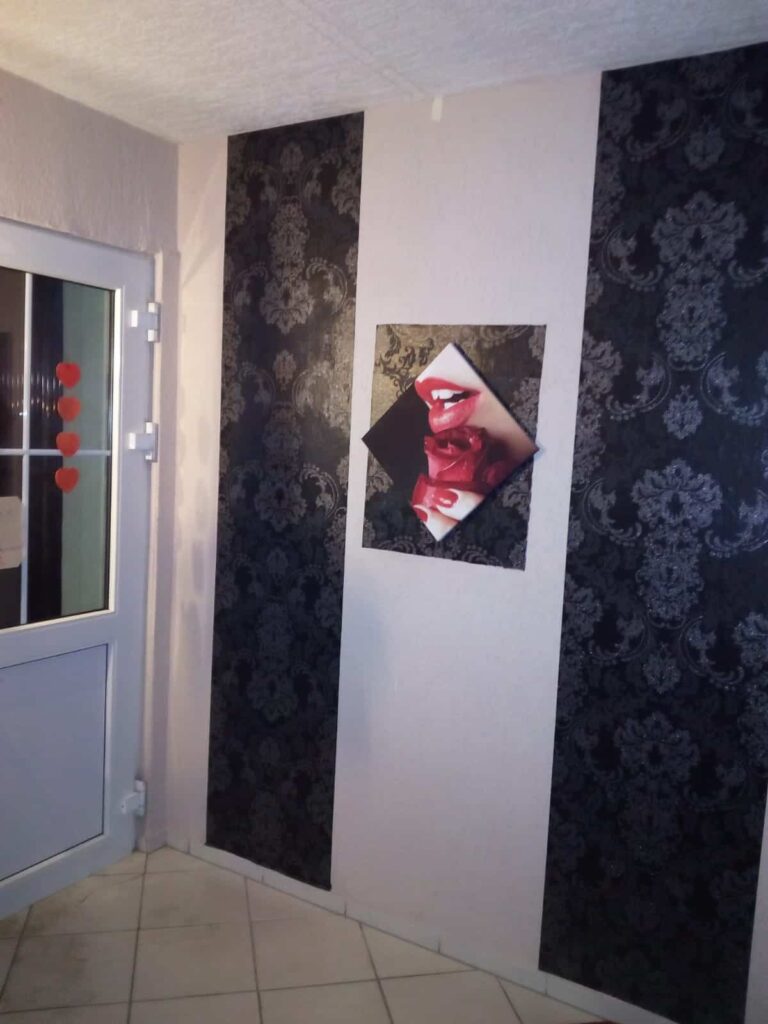 Flur mit dunkler Ornamenttapete und Wandbild mit roten Lippen