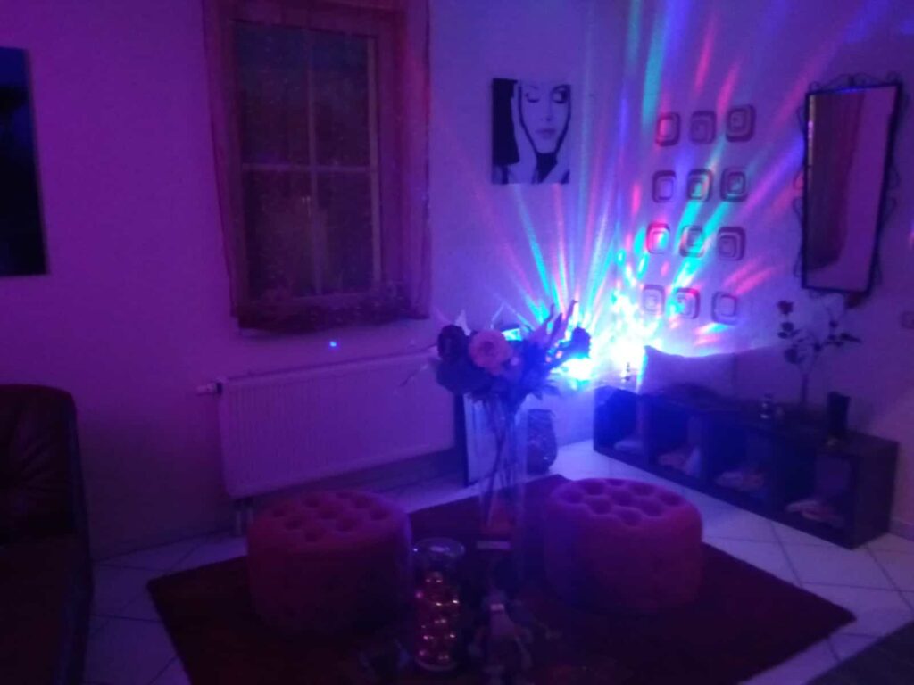 Raum mit Sitzhockern und farbigem Lichtspiel an der Wand